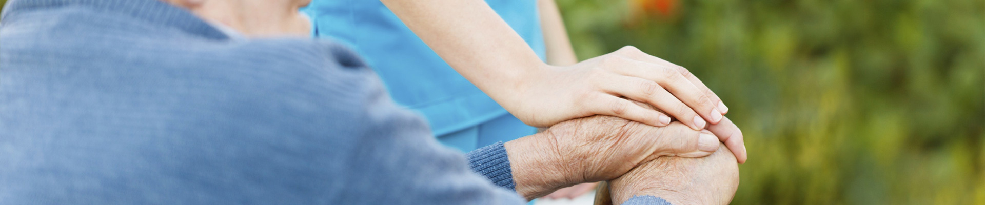 Photo of caretaker's hands lovingly placed on elderly hands
